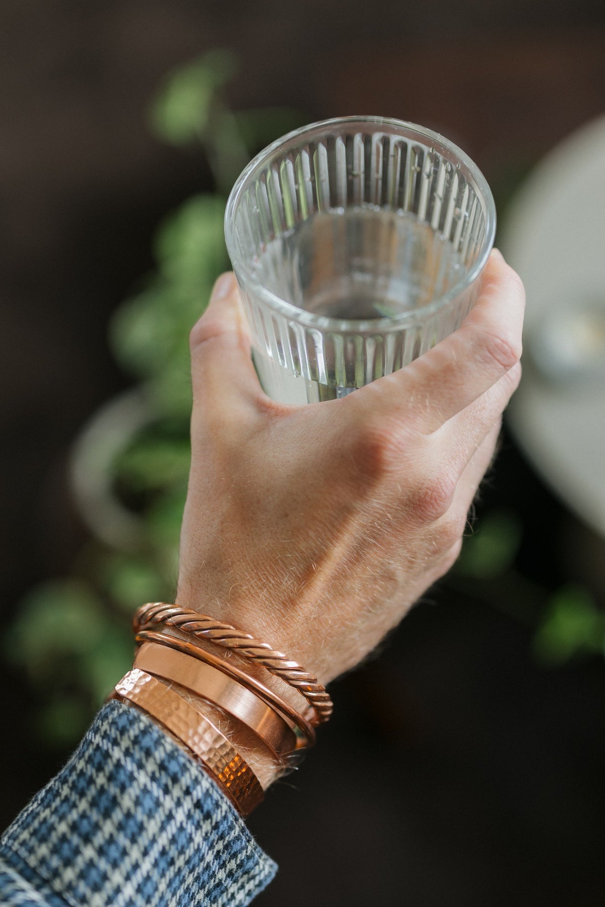 Kopero Kupferarmband, alle vier Ausführungen zusammen an einem Handgelenk, mit einem Glas Wasser in der Hand