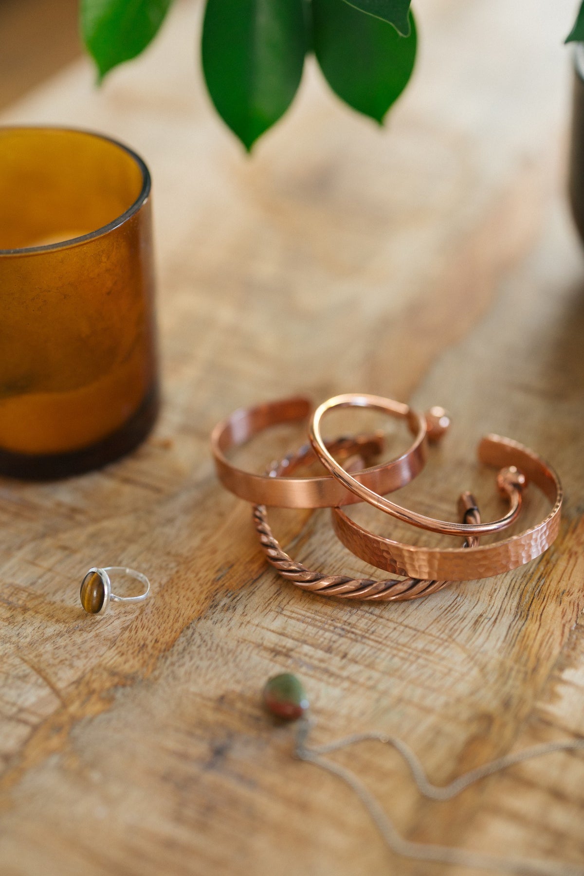 Kopero Kupferarmband, alle vier Ausführungen zusammen auf einem Holztisch mit einer Kerze und einem Ring
