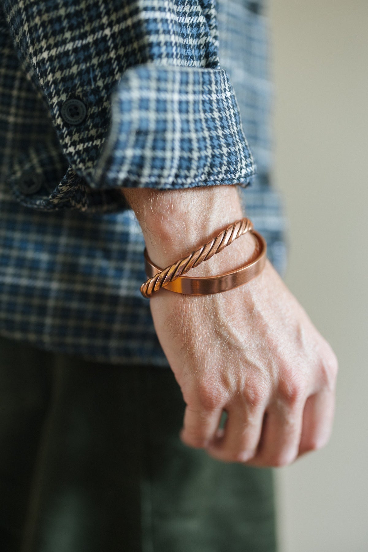 Kopero Kupferarmband Gedreht, am Handgelenk über einem karierten Hemdärmel, zusammen mit einem glatten Armband