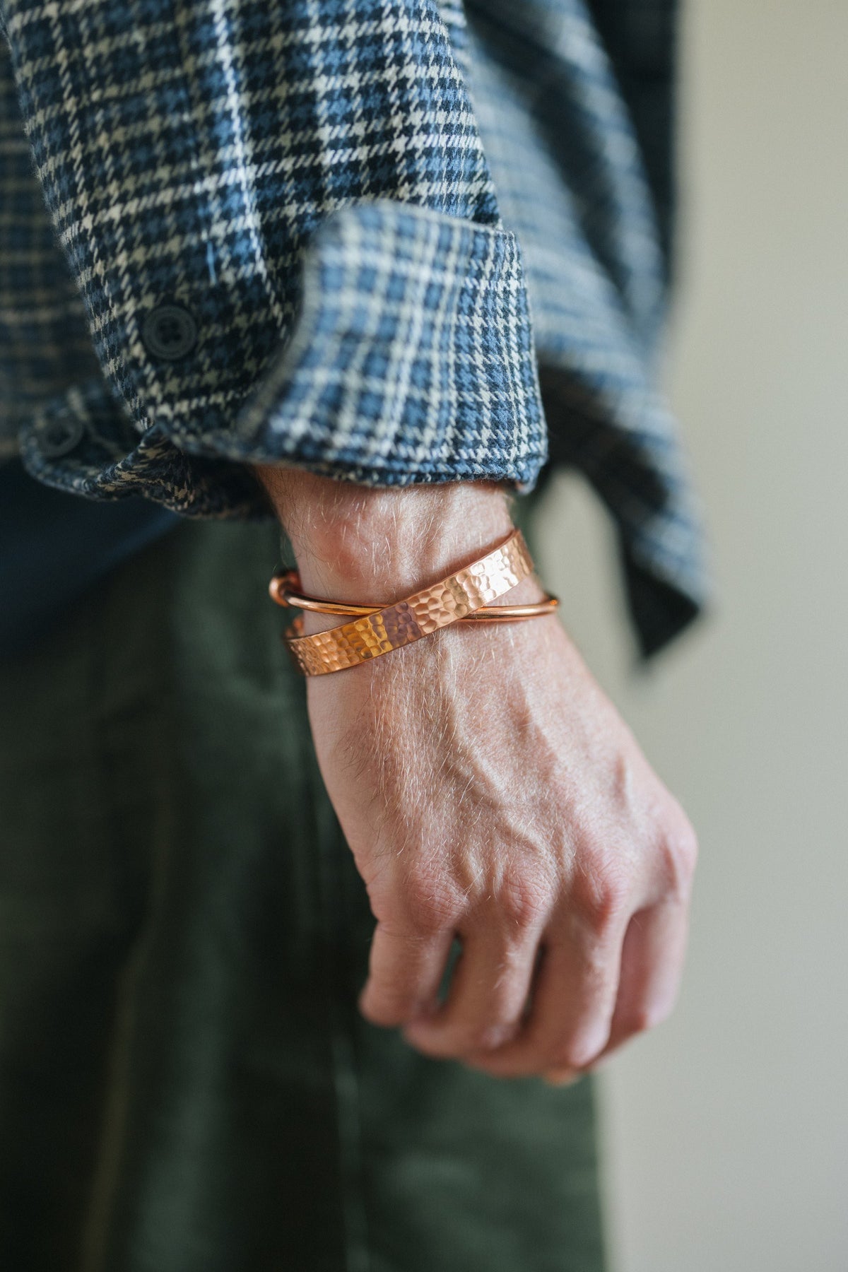 Kopero Kupferarmband Gehämmert, am Handgelenk über einem karierten Hemdärmel, zusammen mit einem glatten Armband