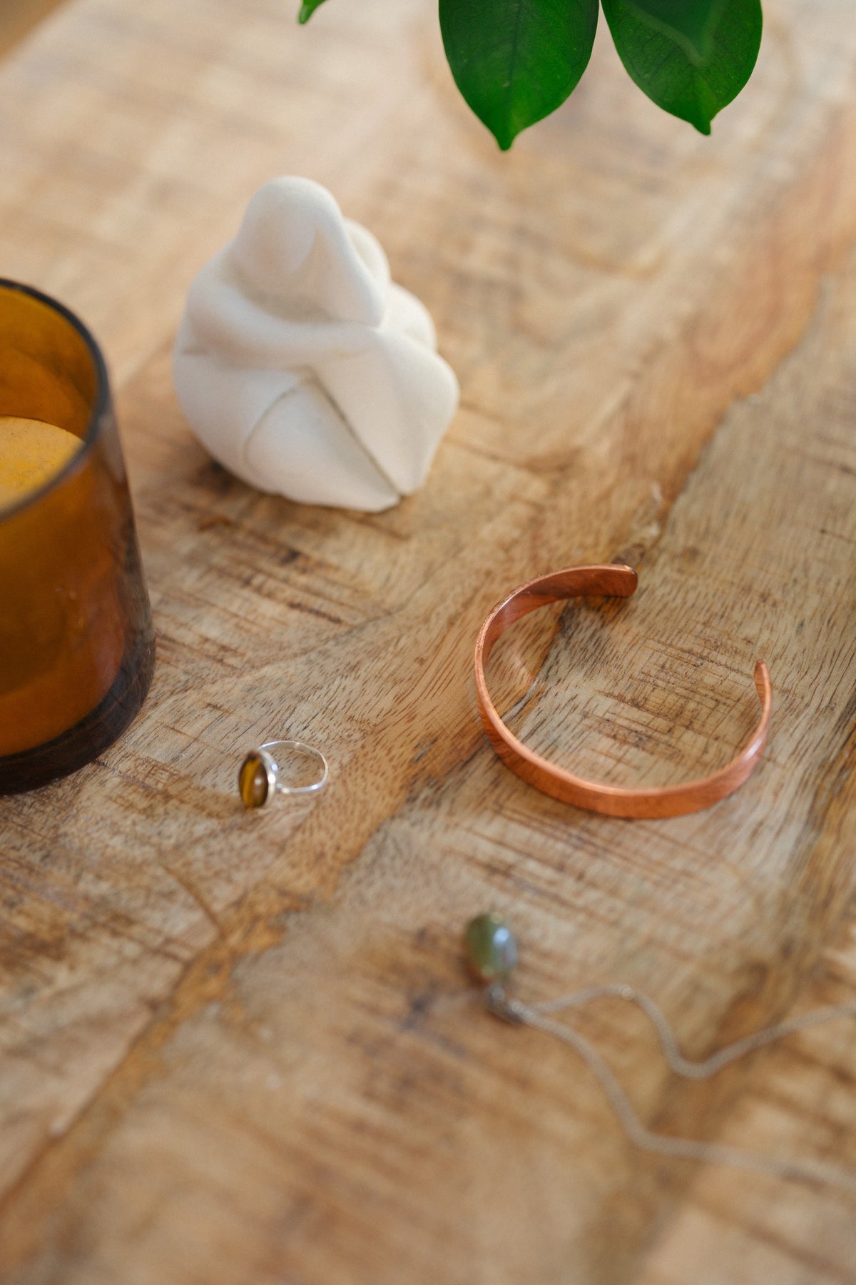 Kopero Kupferarmband Glatt, auf einem Holztisch neben einer Figur und einem Ring