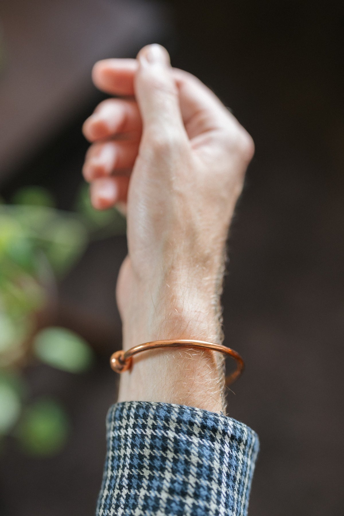 Kopero Kupferarmband Rund, am Handgelenk, mit der Hand nach oben vor einem dunklen Hintergrund