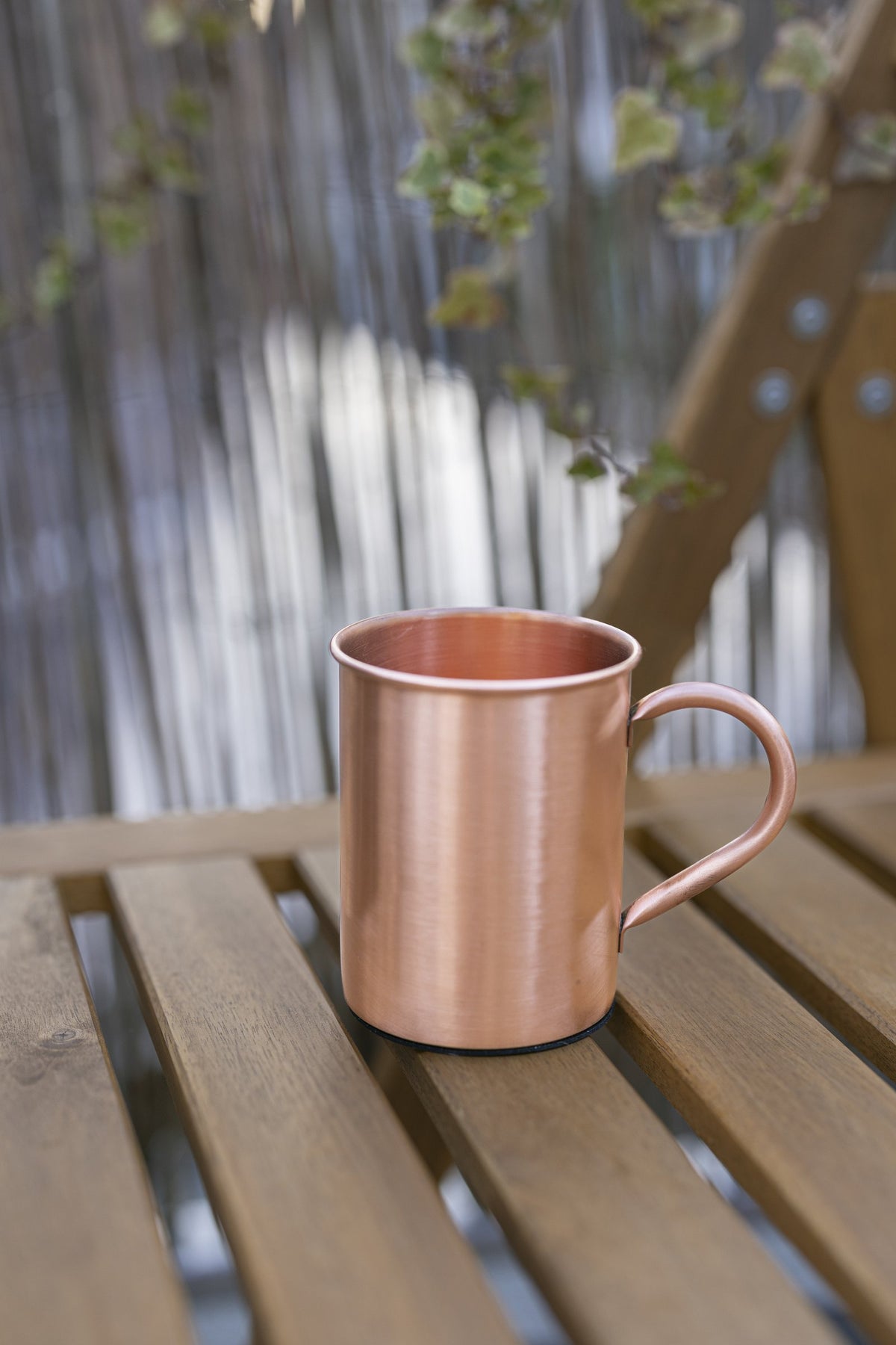 Kopero Kupfertasse Glatt, 400 ml, auf einer Holzgartenbank