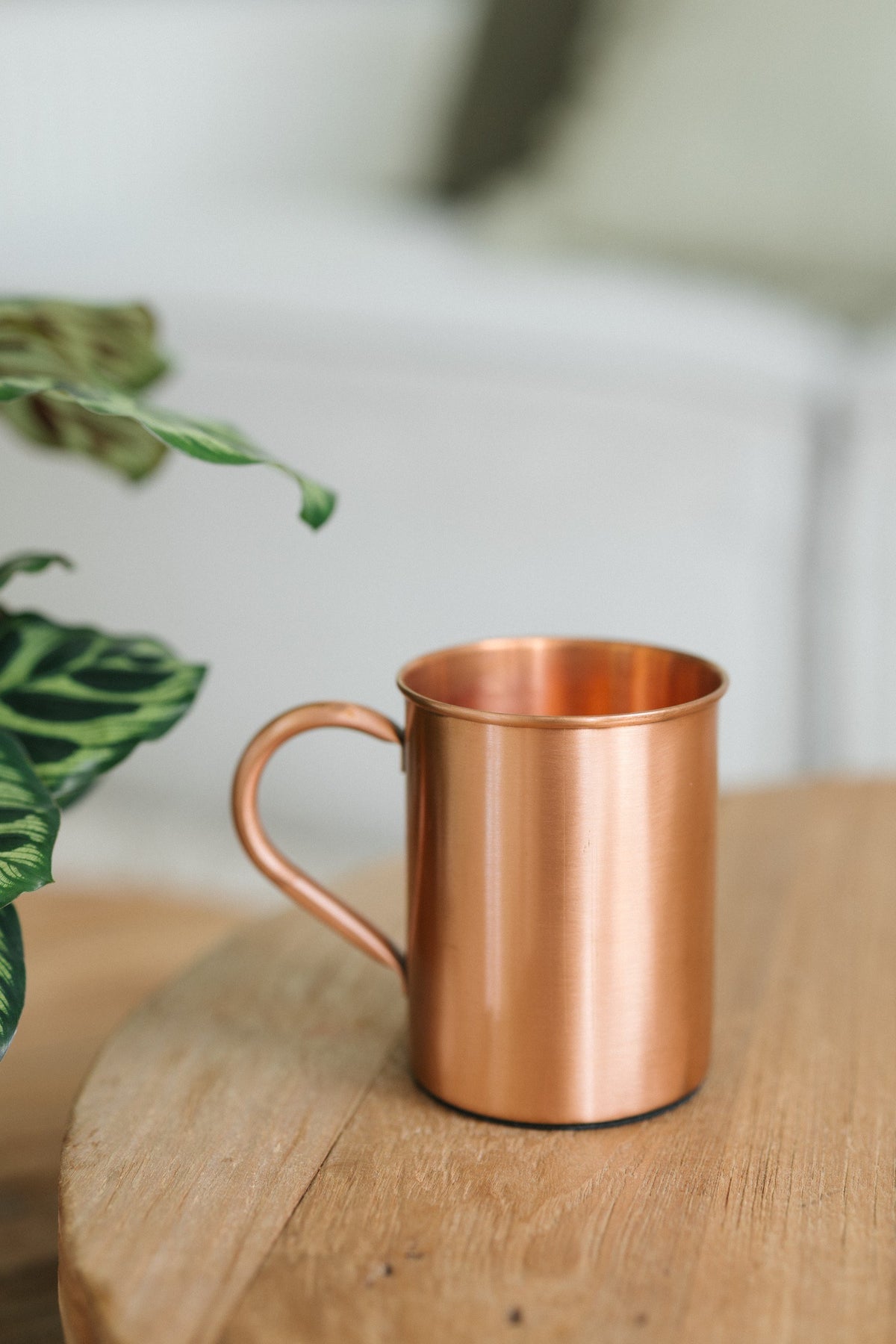 Kopero Kupfertasse Glatt, auf einem runden Holztisch vor einem Sofa