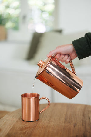 Kopero Kupfertasse Glatt, während Wasser aus einer kupfernen Kanne hineingegossen wird