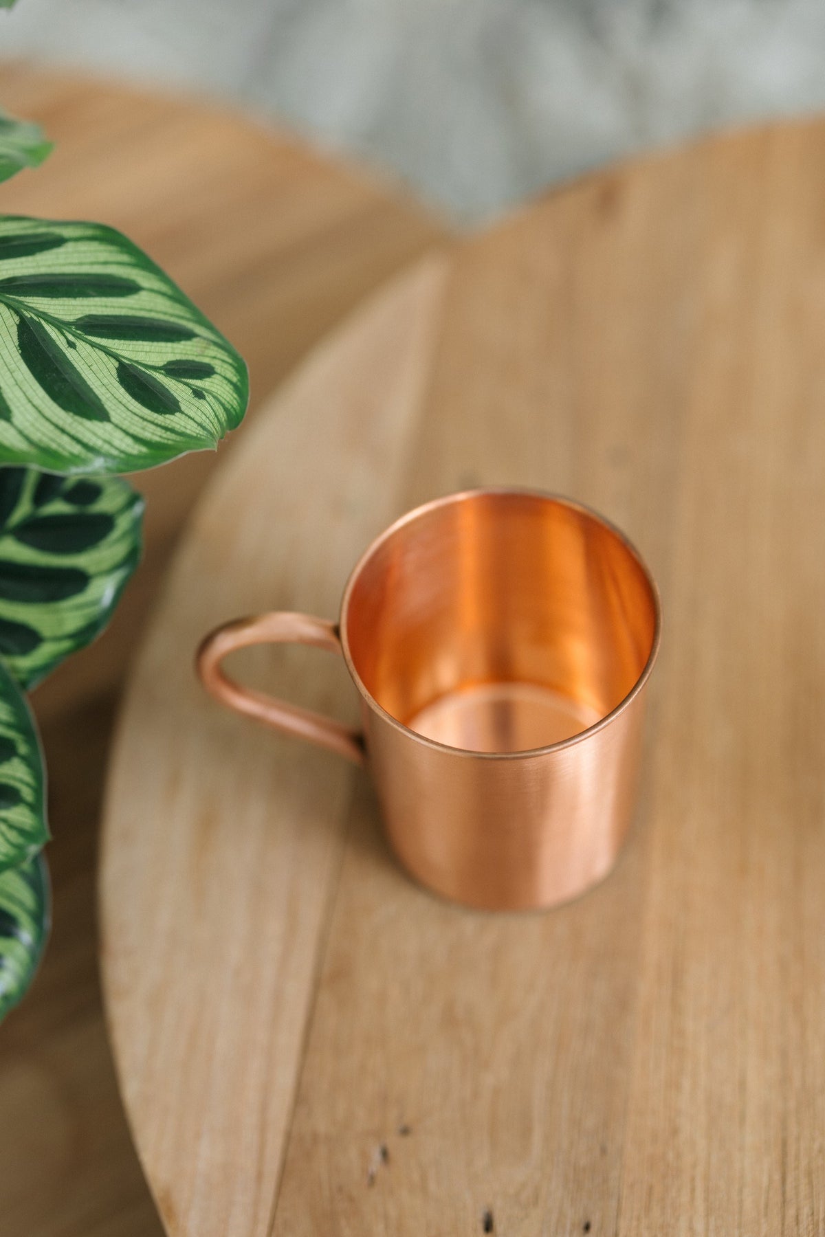 Kopero Kupfertasse Glatt, auf der Seite liegend auf einem runden Holztisch