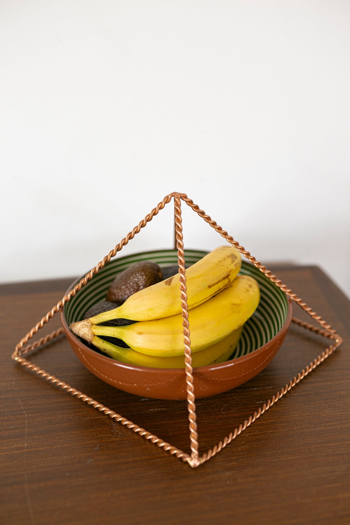 Kopero Kupfer-Pyramide-Energizer Gedreht, 23,56 cm, schräger Winkel über einer Schale Obst