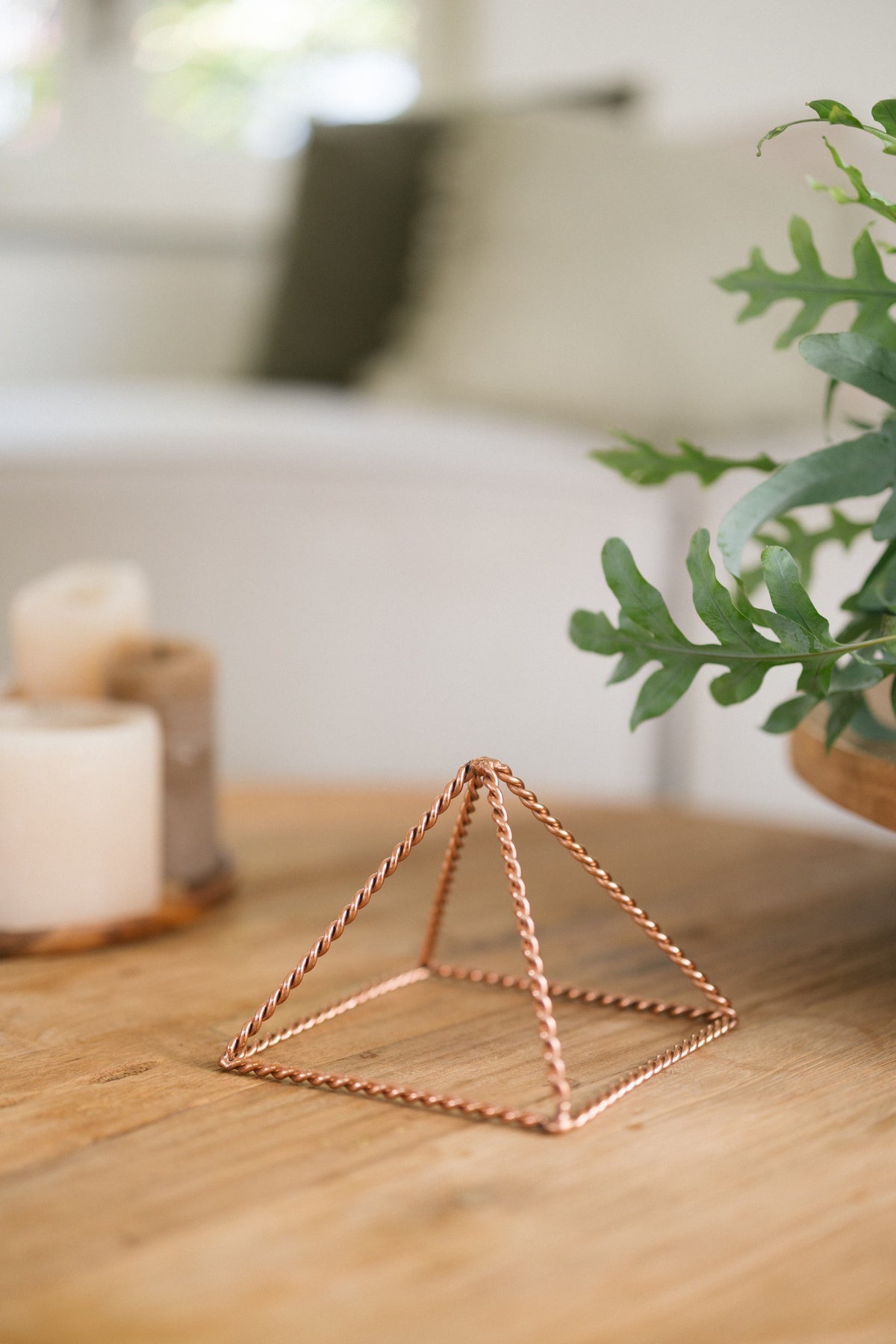 Kopero Kupfer-Pyramide Energizer Gedreht Klein (14,56 cm), auf einem Holztisch neben Kerzen