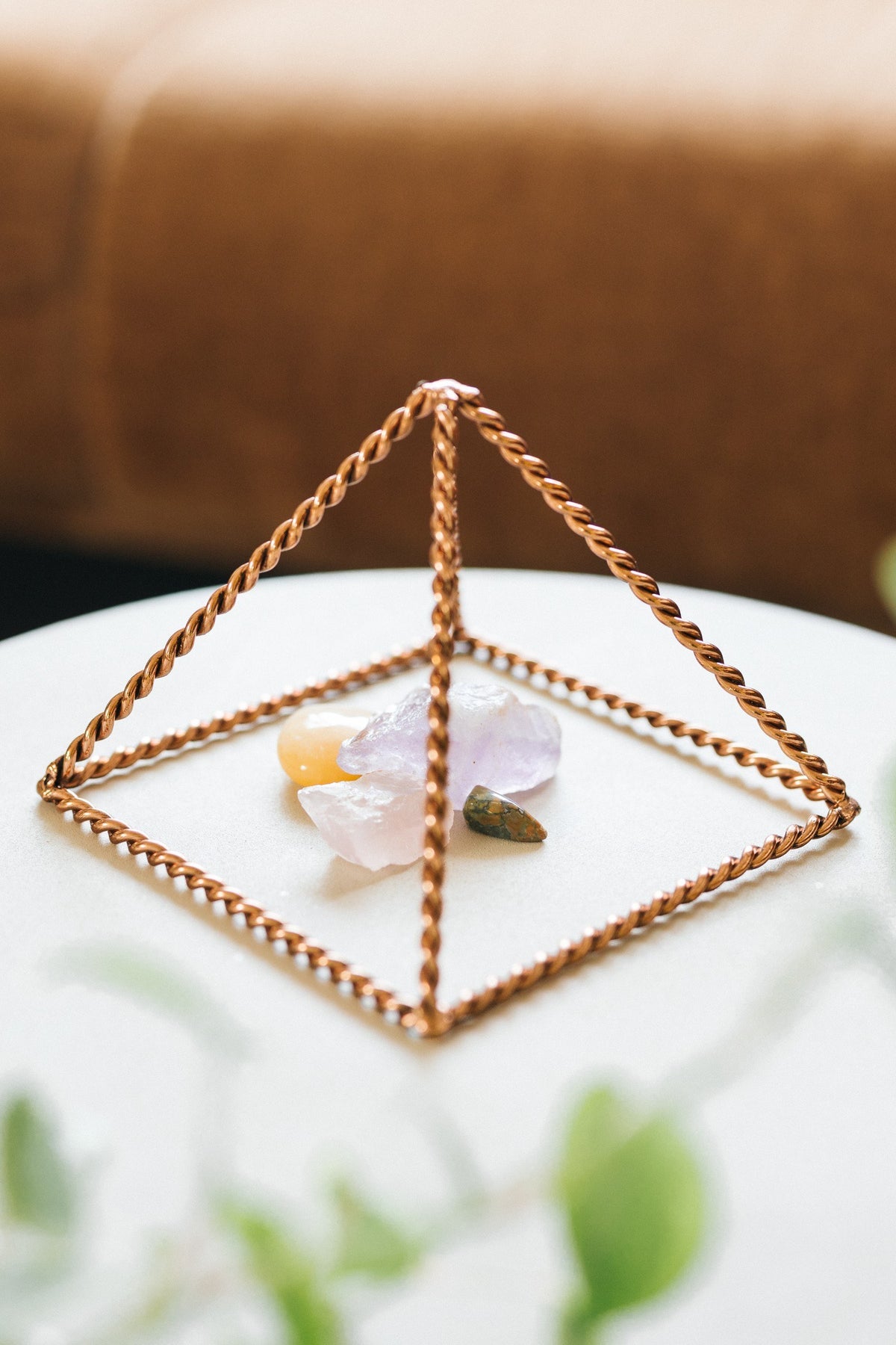 Kopero Kupfer-Pyramide Energizer Gedreht Klein (14,56 cm), mit Edelsteinen darunter auf einem weißen Tischchen