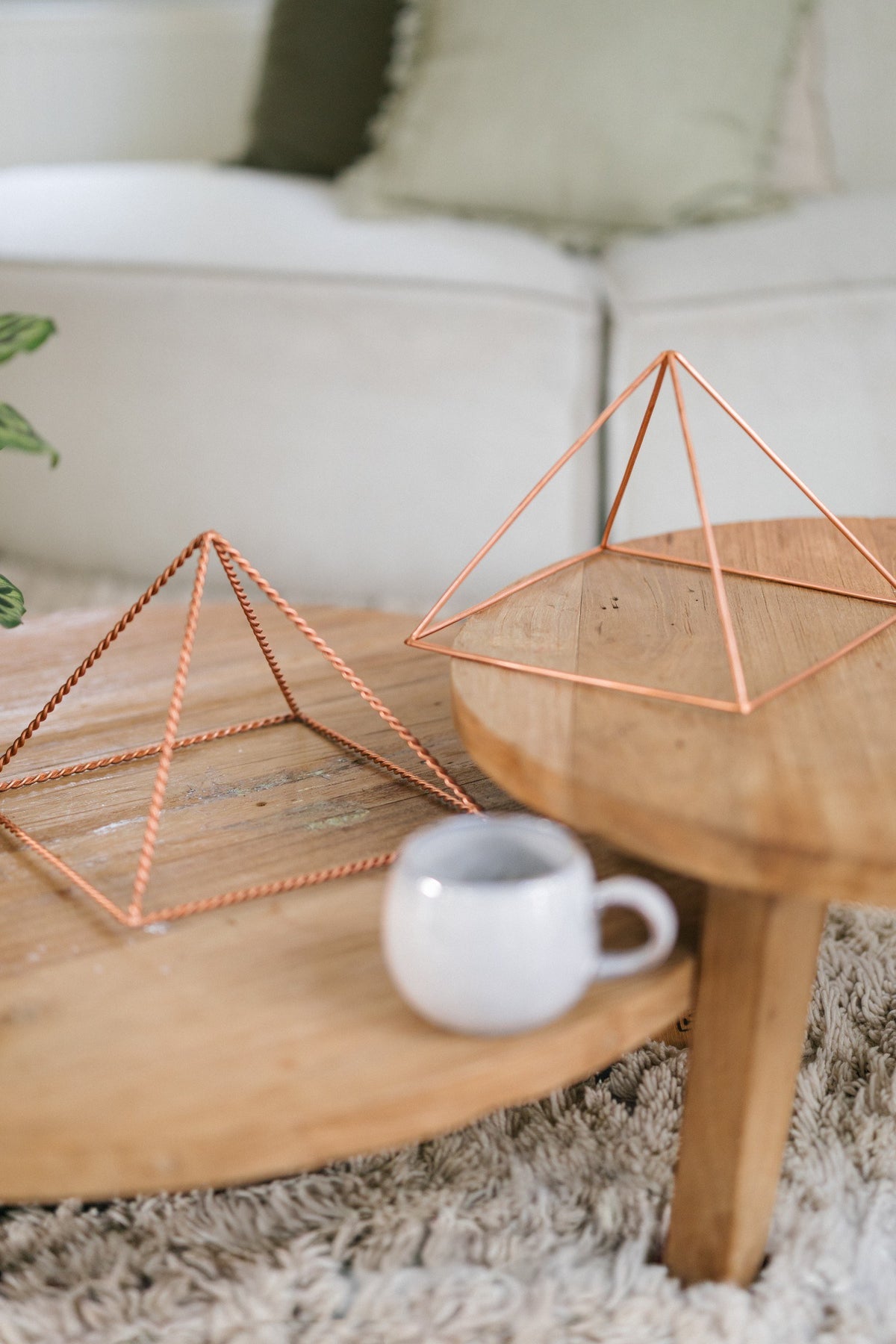 Kopero Kupfer-Pyramide Energizer Glatt Groß (23,56 cm), eine gedrehte und eine glatte große Pyramide auf zwei Holztischen mit einer Tasse