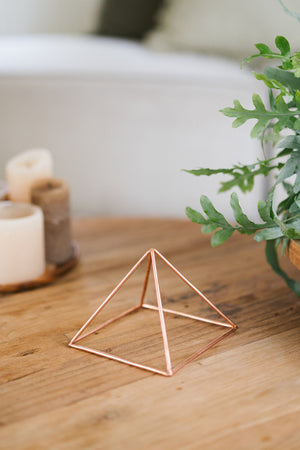 Kopero Kupfer-Pyramide Energizer Glatt Klein (14,56 cm), auf einem Holztisch neben Kerzen