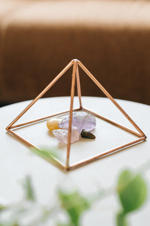 Kopero Kupfer-Pyramide Energizer Glatt Klein (14,56 cm), mit Edelsteinen darunter auf einem weißen Tischchen
