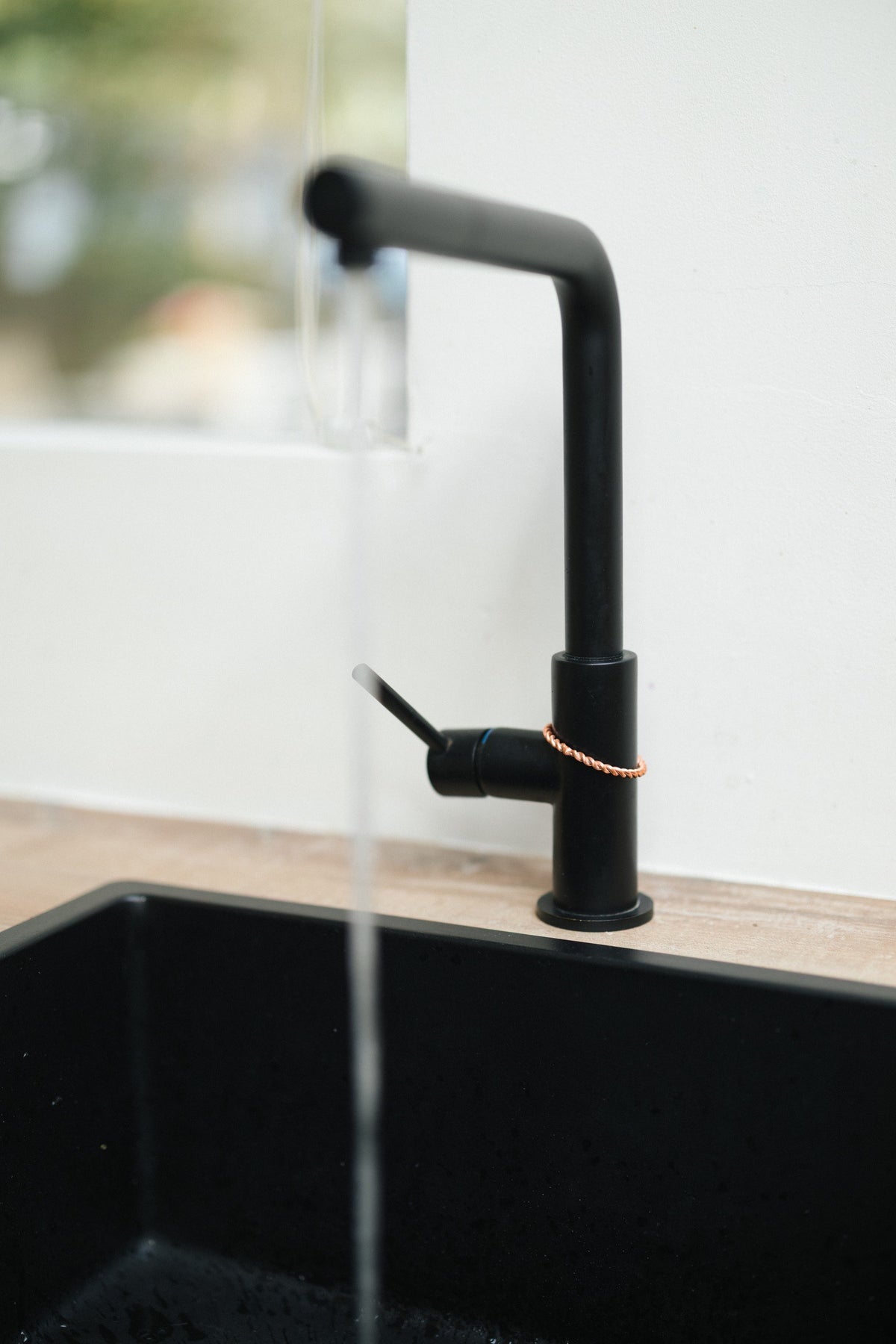 Kopero Kupfer-Tensorring, um den Wasserhahn eines schwarzen Küchenhahns mit fließendem Wasser