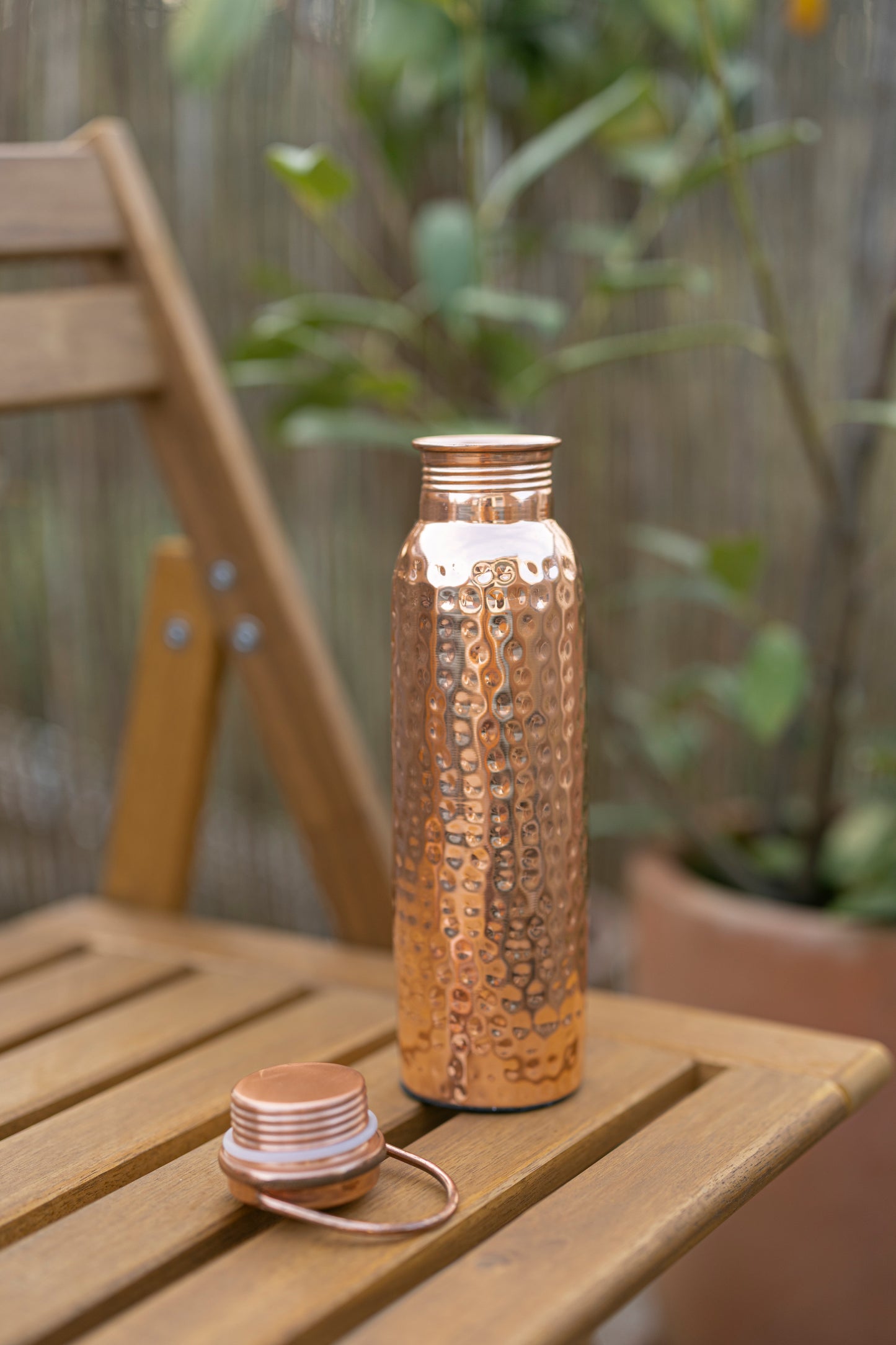 Kopero Kupfer-Wasserflasche Gehämmert mit abgenommenem Deckel auf einem Holzgartenstuhl