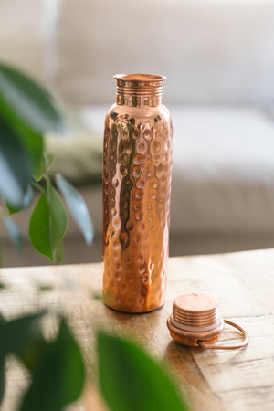 Kopero Kupferflasche Gehämmert, stehend auf einem Holztisch vor einem Sofa, mit der losen Kappe daneben
