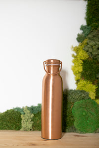 Kopero Kupfer-Wasserflasche Glatt, 900 ml, aufrecht auf einem Holztisch vor einem Moosgrund