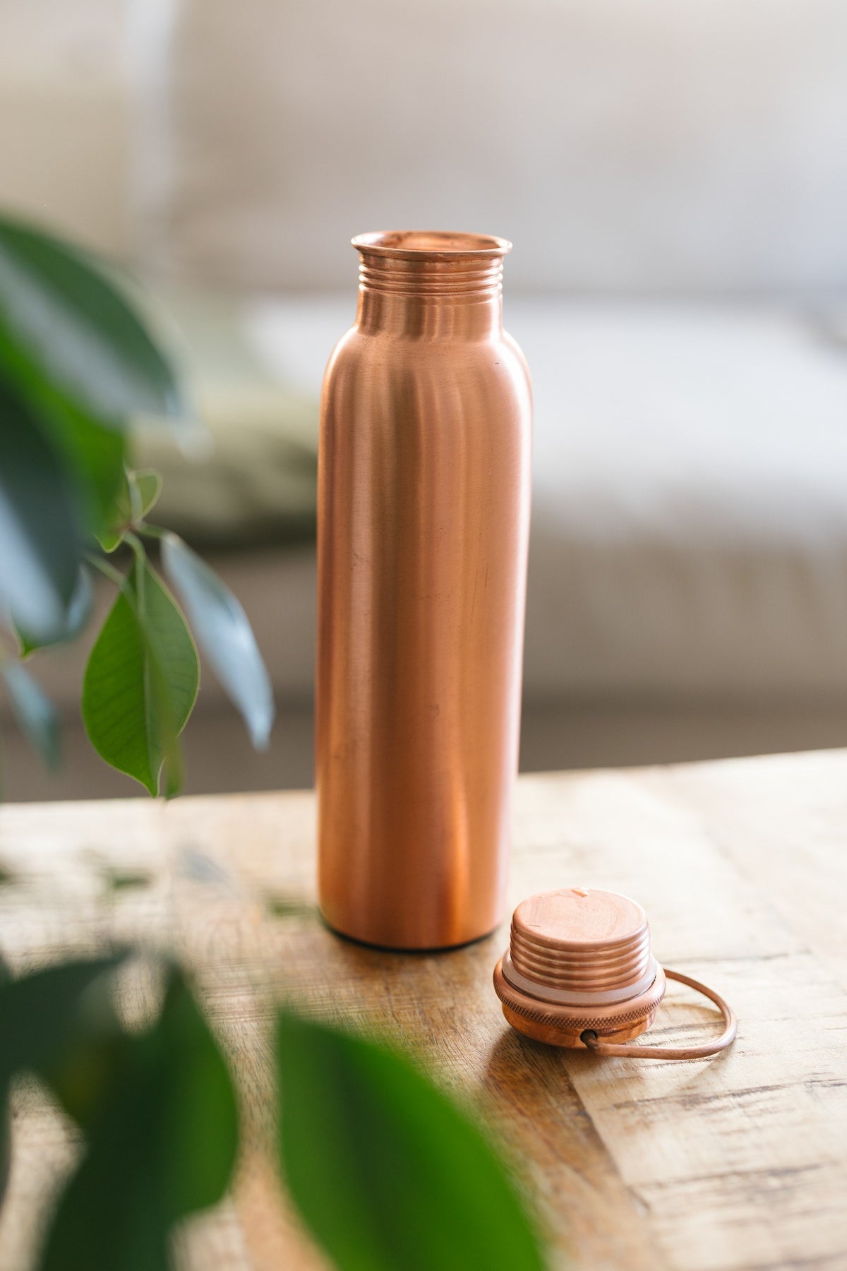 Kopero Kupferflasche Glatt, stehend auf einem Holztisch vor einem Sofa, mit der losen Kappe daneben