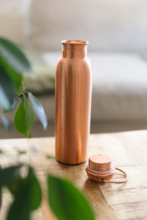Kopero Kupferflasche Glatt, stehend auf einem Holztisch vor einem Sofa, mit der losen Kappe daneben
